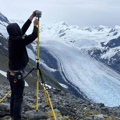 Surveyor adjusting a GPS device on a mountain ridge.