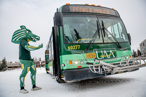 Spirit the Seawolf enters the new ɫƬ-wrapped People Mover bus on the ɫƬ campus in winter.
