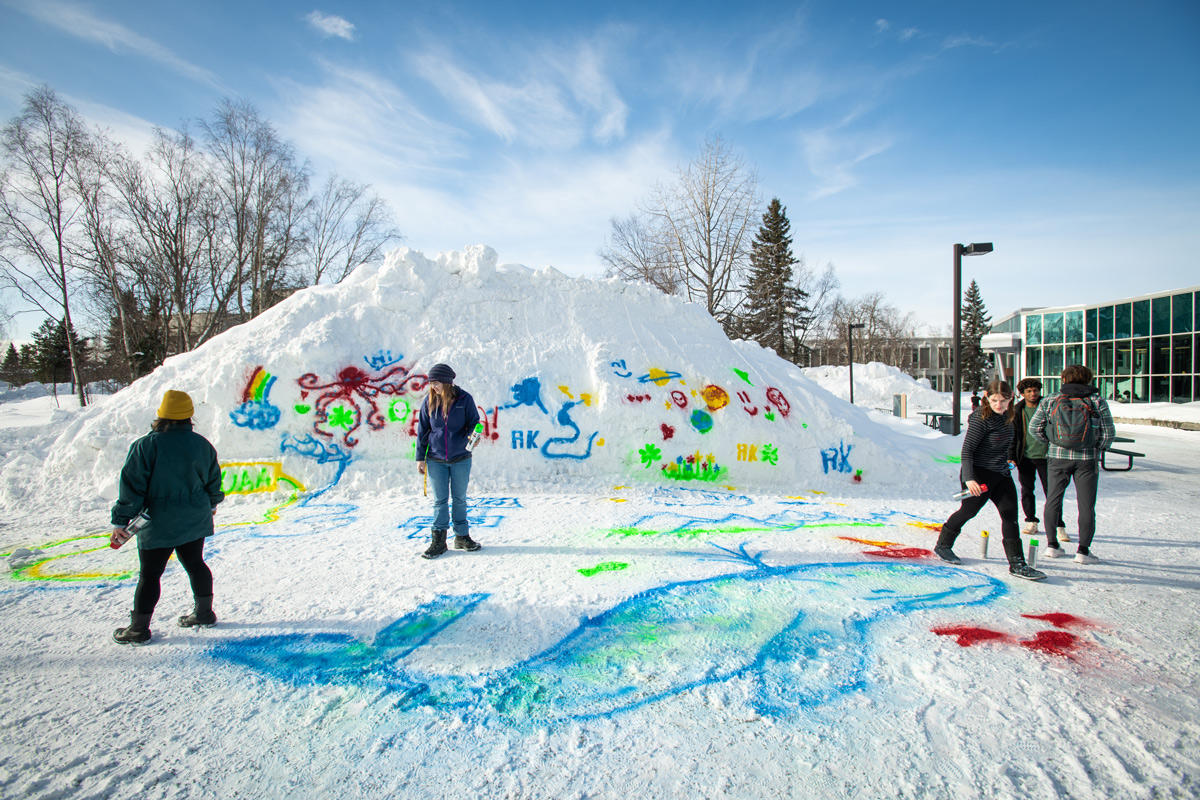 Allyson Brokaw, Maureen Meyer, and Cassidy Johnson paint snow graffiti during 做爱色情片's 2023 Winterfest Art & Music in the Quad.